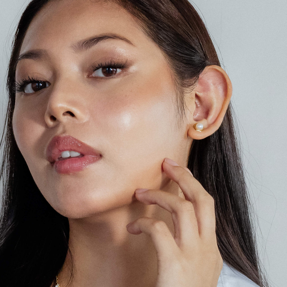 Woman touching her cheek with a pearl earring visible