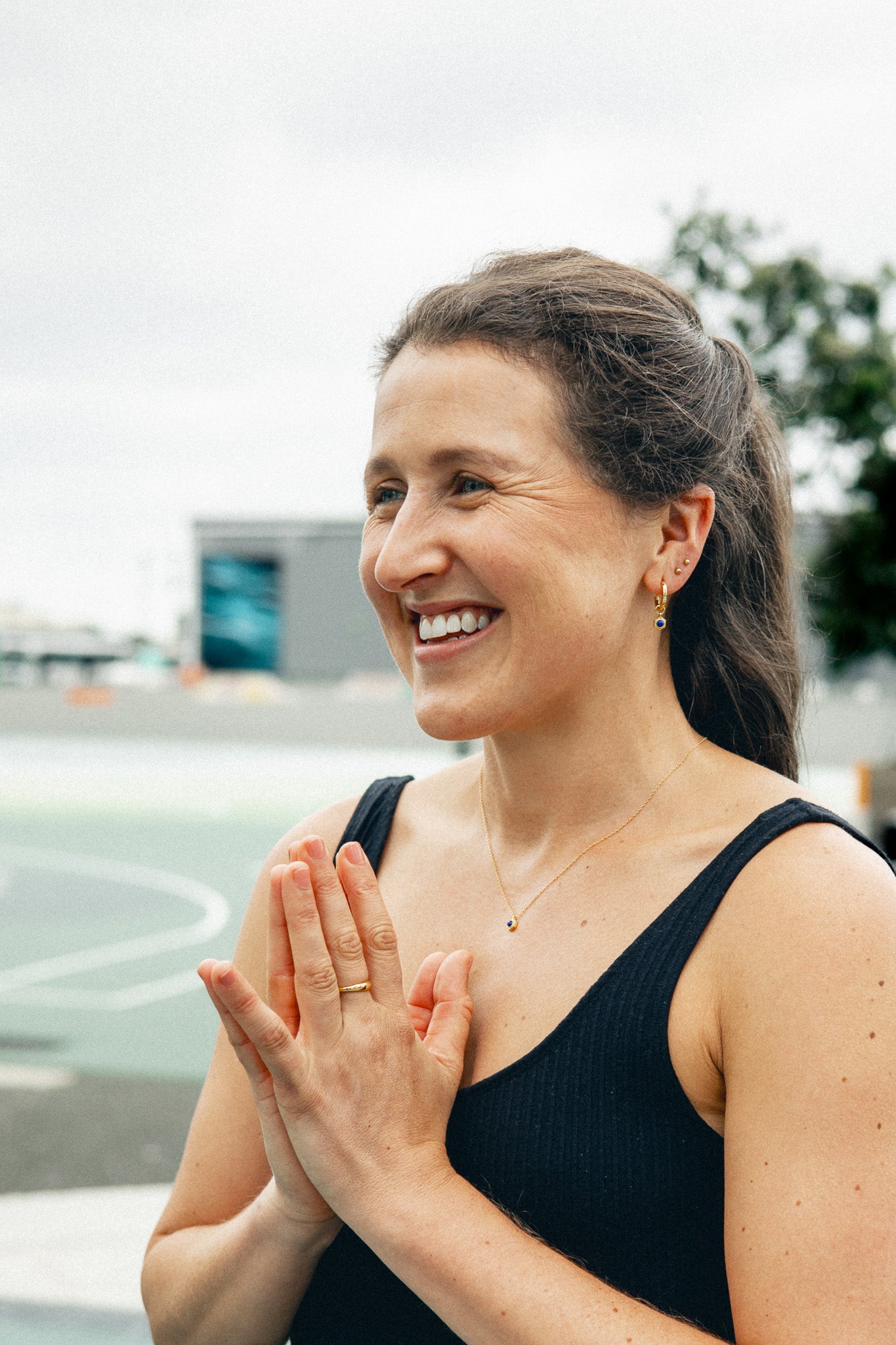 Lifestyle Shot - Close-up of model smiling, wearing necklace and drop earring.