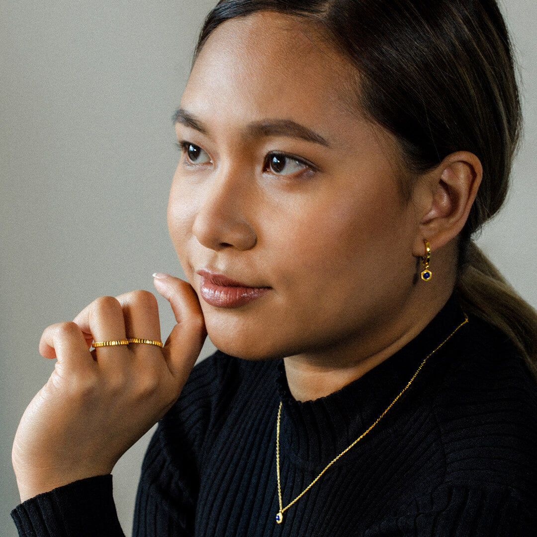 Woman wearing gold jewelry against a neutral background