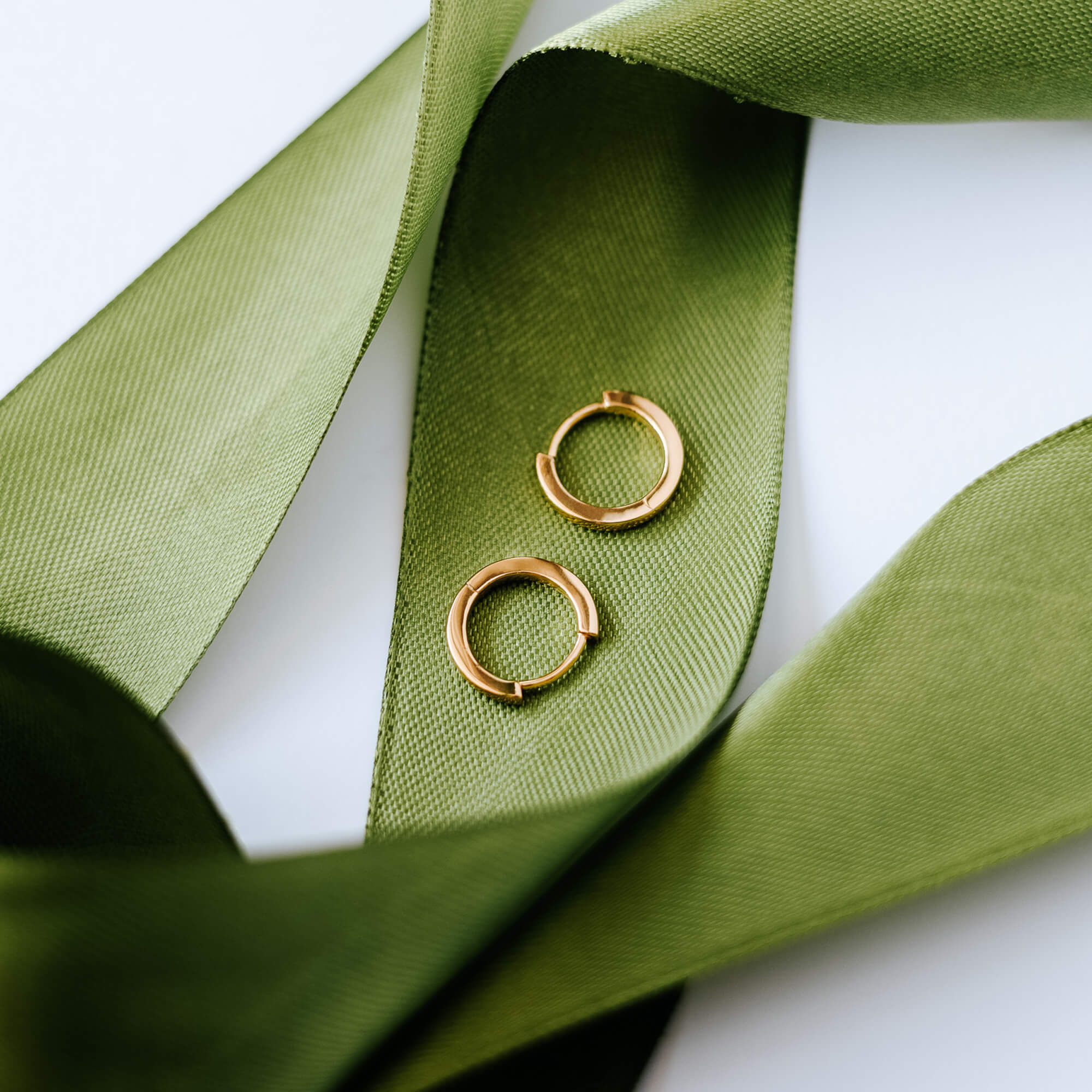 Gold hoop earrings on a green satin ribbon