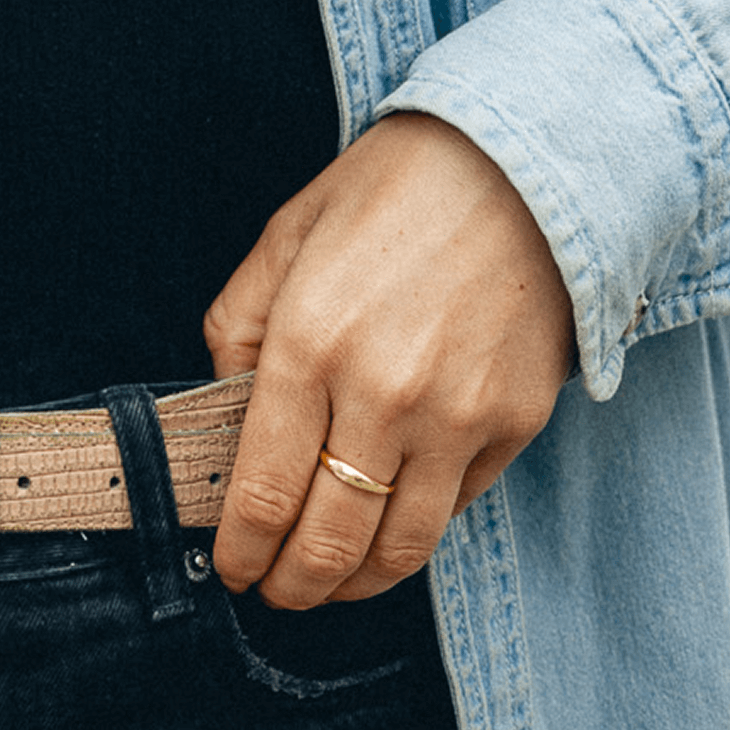 Ring Close-up - Model wearing a smooth, slim dome gold ring with a denim shirt.