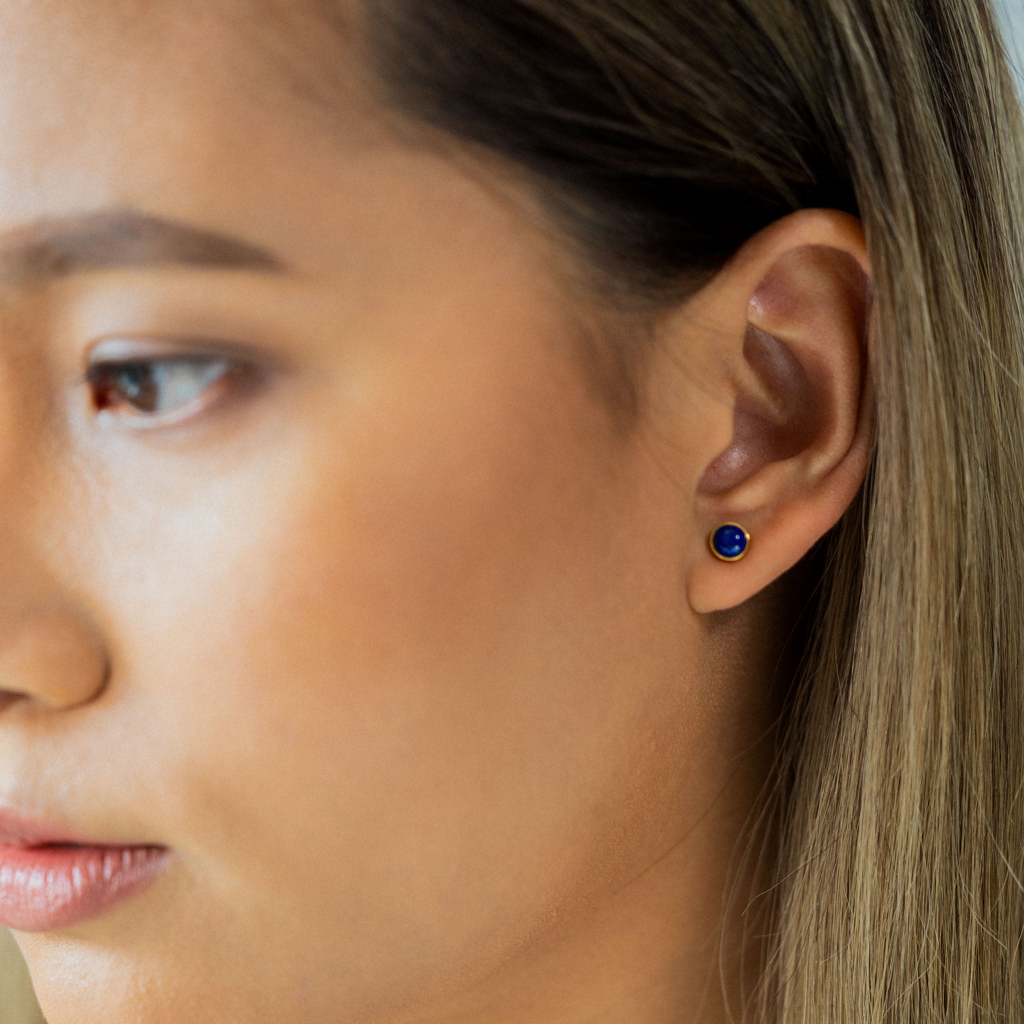 Adorn your ear with BY TONIN's captivating Bel e Viv gold round stud earring, beautifully showcasing a deep blue lapis lazuli gemstone in a striking close-up profile.