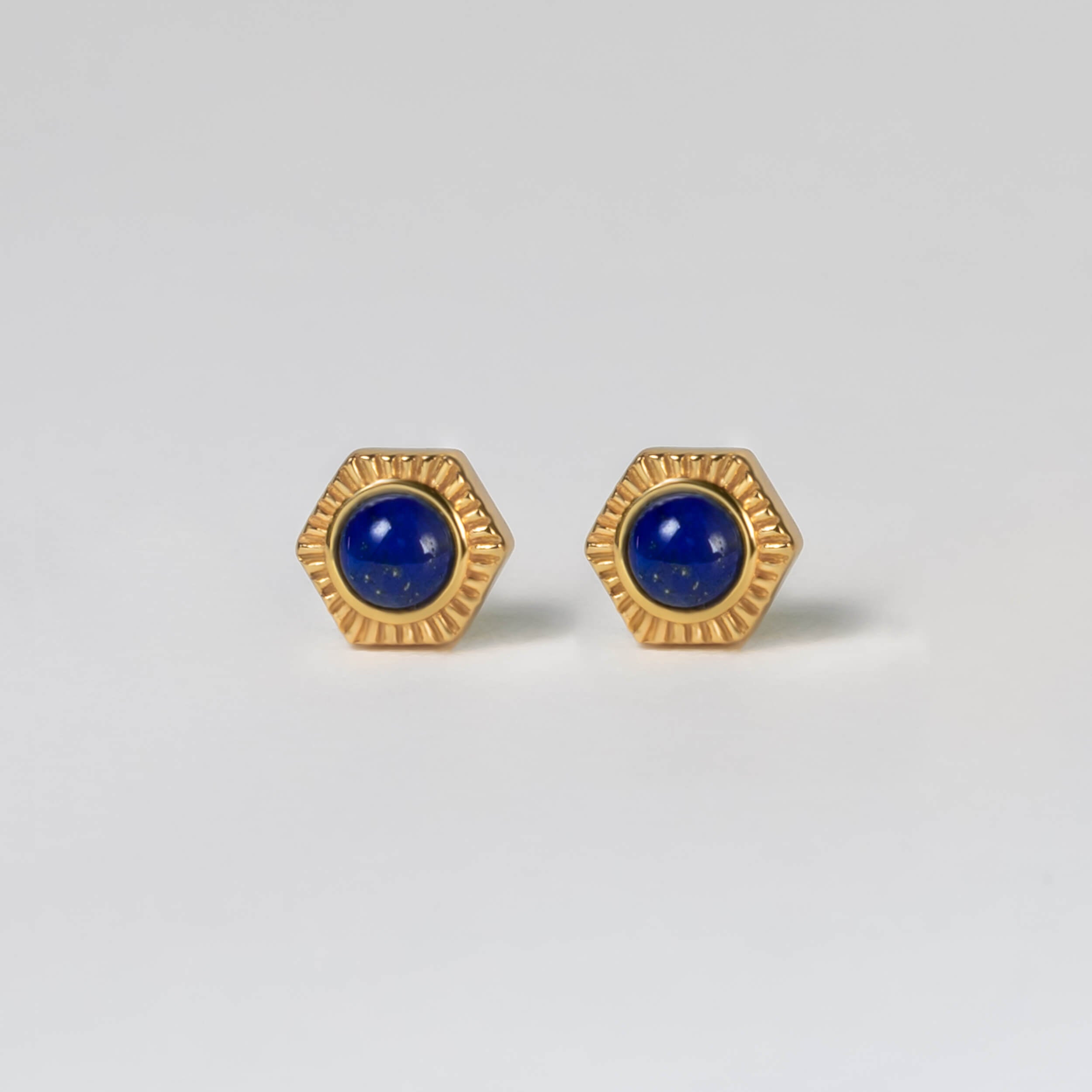 Make a bold statement with BY TONIN Belle Viv gold hexagonal stud earrings, featuring captivating deep blue lapis lazuli inlays for striking sophistication