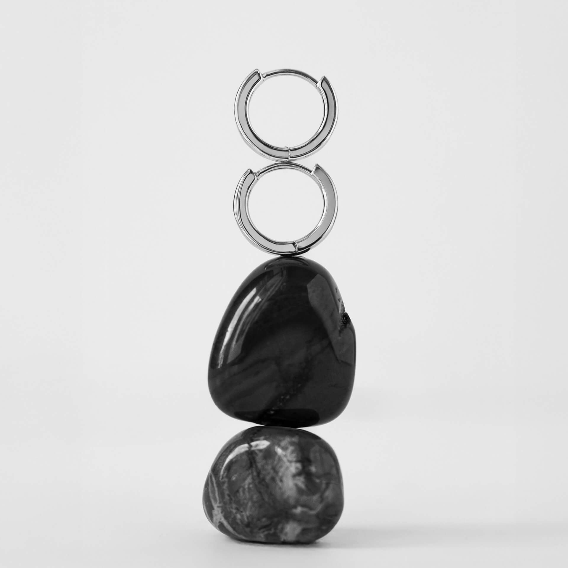 Pair of hoop earrings with black stones on a white background