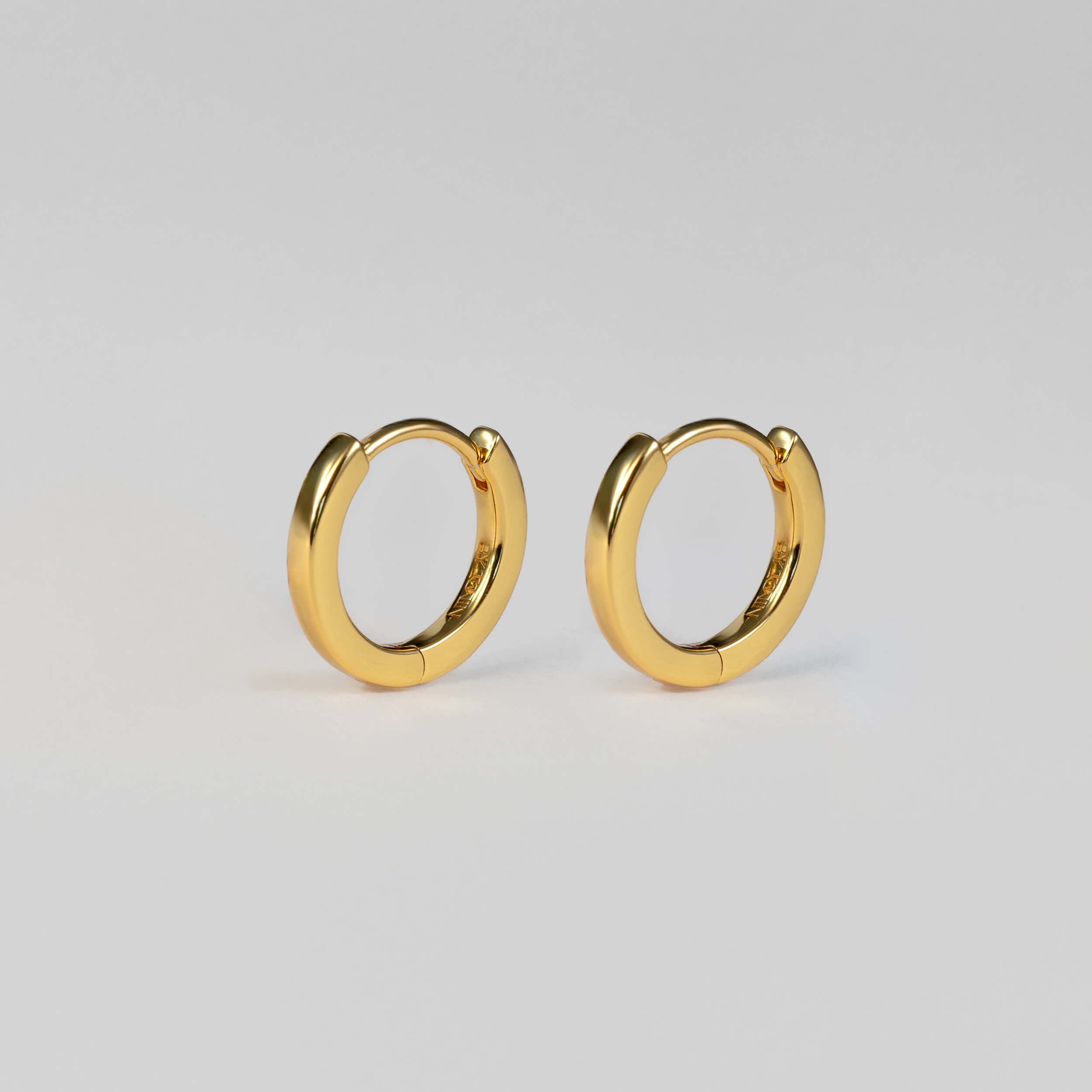 Elevate your everyday style with BY TONIN Heritage gold mini hoop earrings, featuring a flawless, polished finish for timeless elegance.