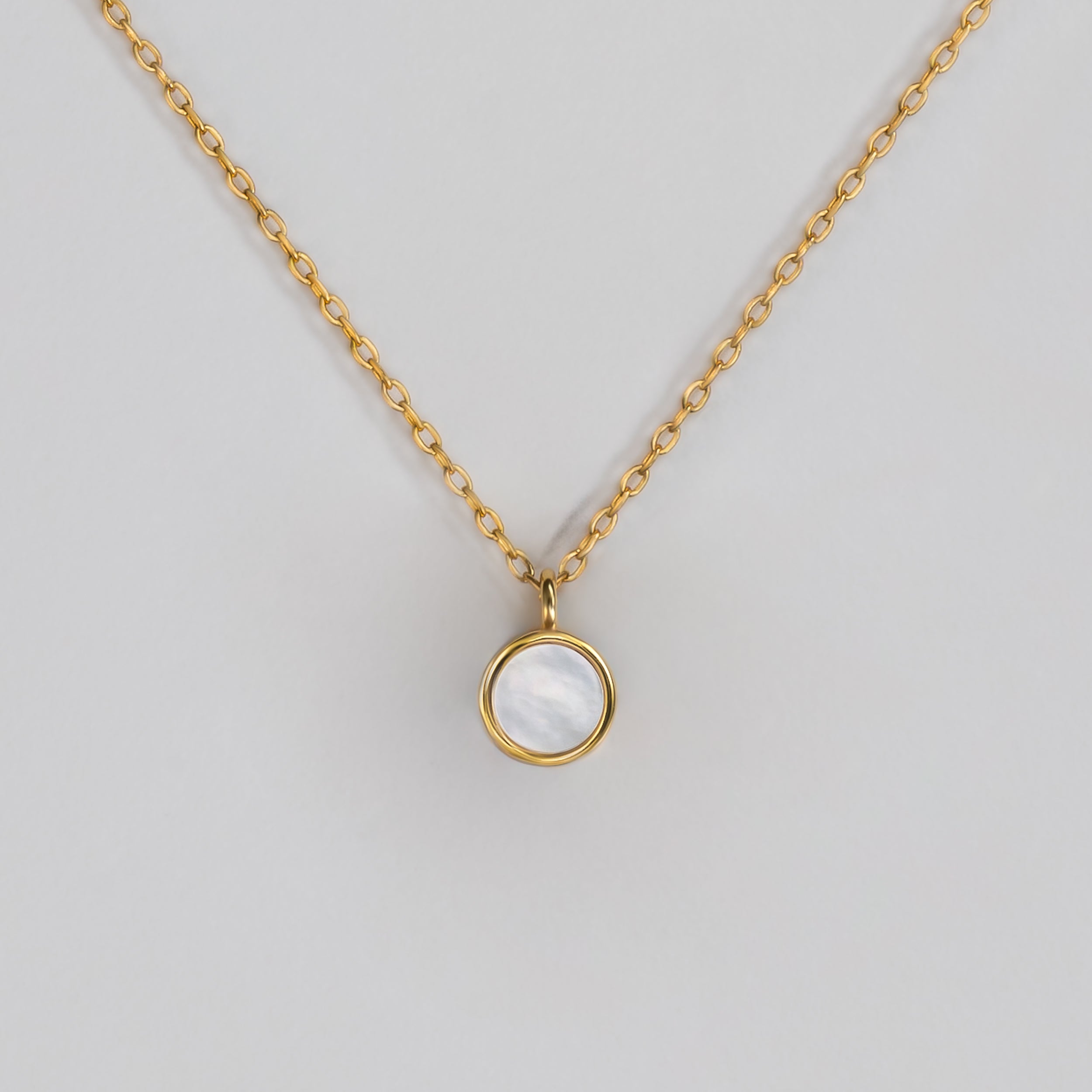 BY TONIN Heritage gold necklace with a luminous round mother of pearl pendant on white background.