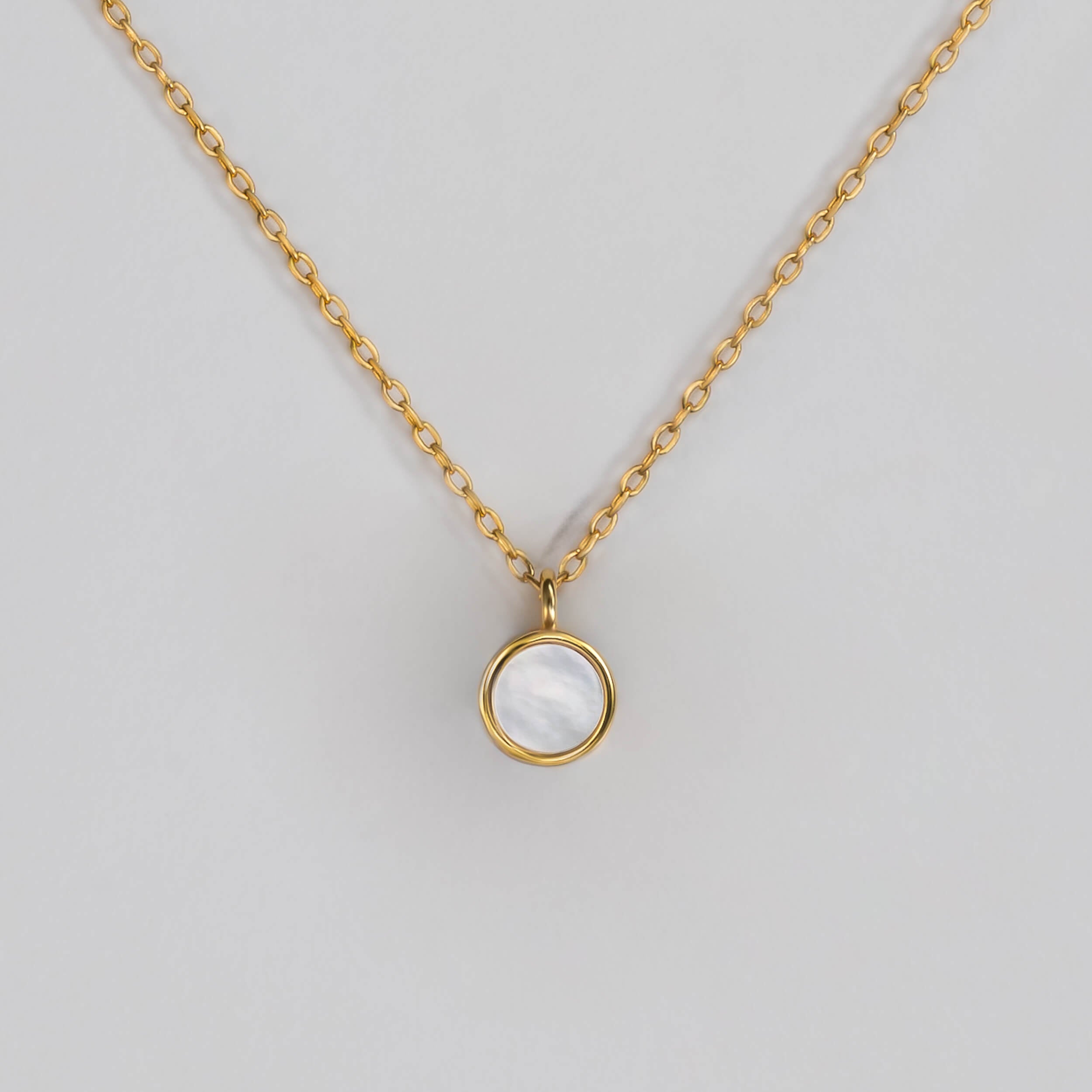 BY TONIN Heritage gold necklace with a luminous round mother of pearl pendant on white background.