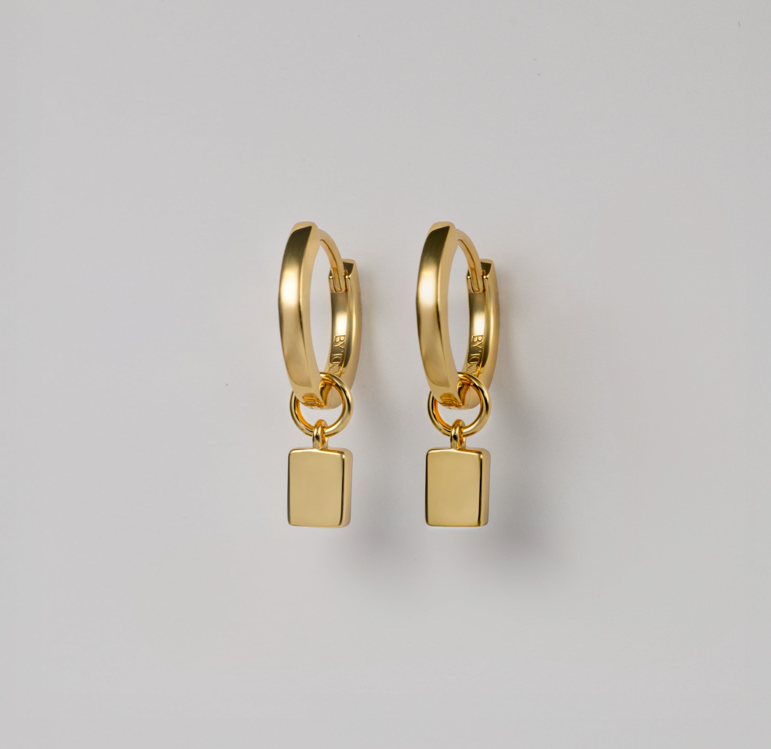 Discover the seamless elegance of BY TONIN Heritage gold mini hoop earrings, showcasing the polished reverse of their modern square charms.