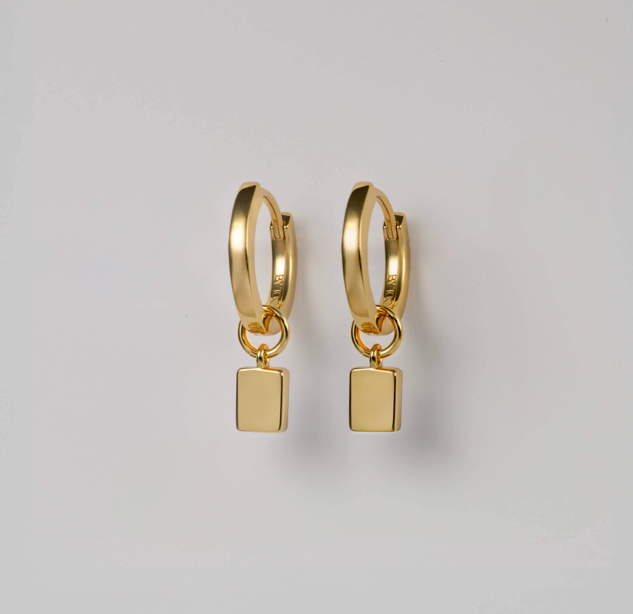Discover the seamless elegance of BY TONIN Heritage gold mini hoop earrings, showcasing the polished reverse of their modern square charms.