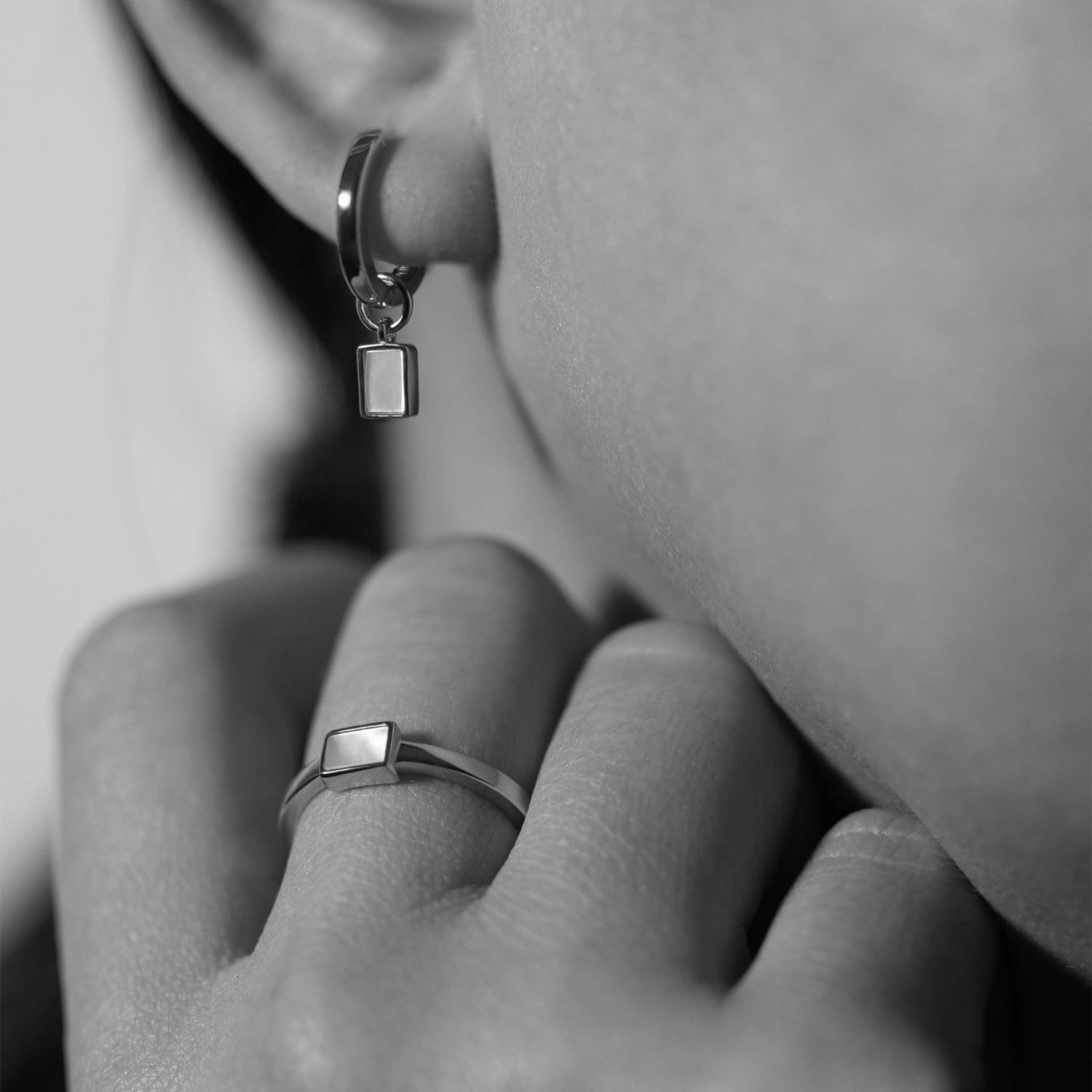 Experience refined elegance with BY TONIN Heritage silver mini hoop earrings and matching rectangular mother of pearl ring, gracefully styled on a model in black and white.