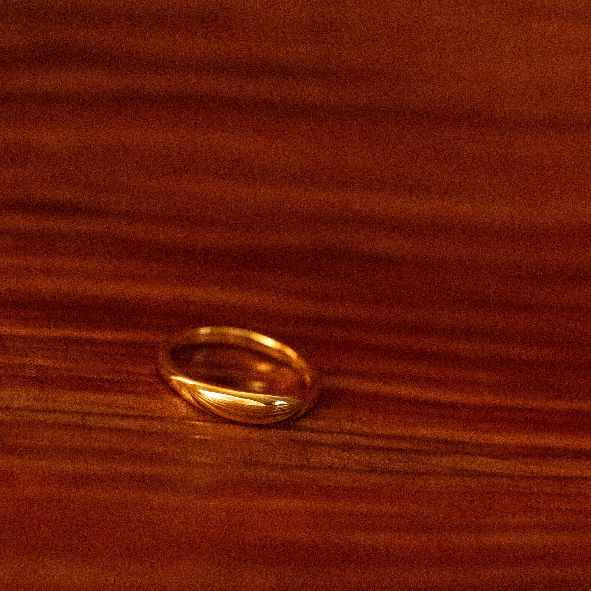 Experience the captivating allure of BY TONIN's Heritage slim gold dome ring, exquisitely displayed on a warm, polished palm surface, a symbol of understated luxury.