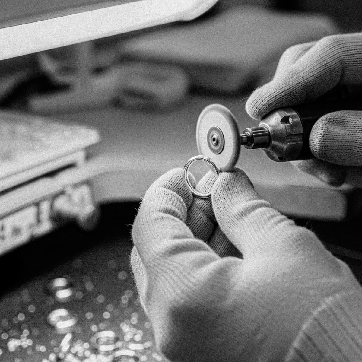 Witness the meticulous craftsmanship of BY TONIN, as a skilled artisan delicately polishes a gold ring with a rotary tool, showcasing dedication to exquisite jewellery making.