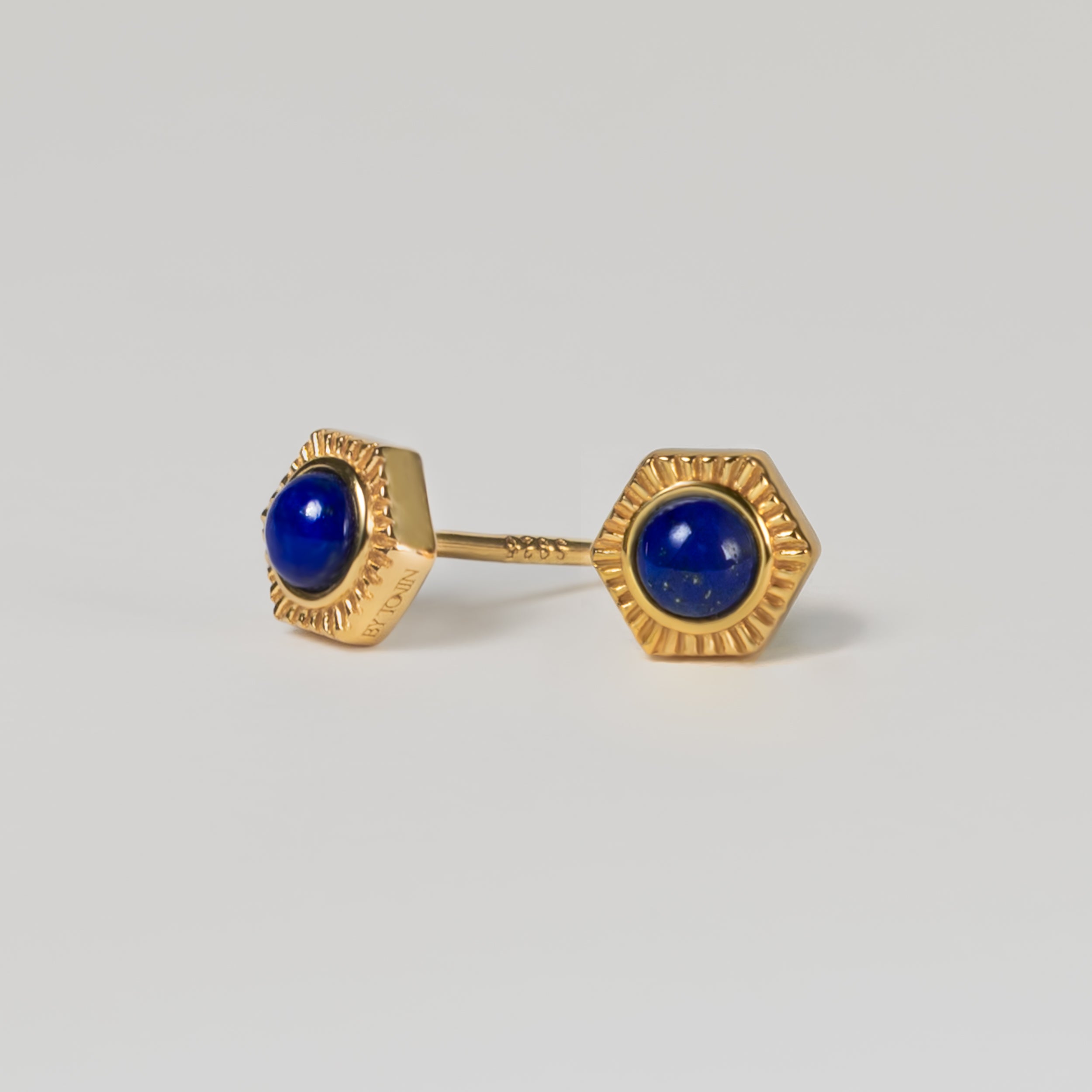 Close-up of BY TONIN's hexagonal gold earrings featuring vibrant blue lapis lazuli.