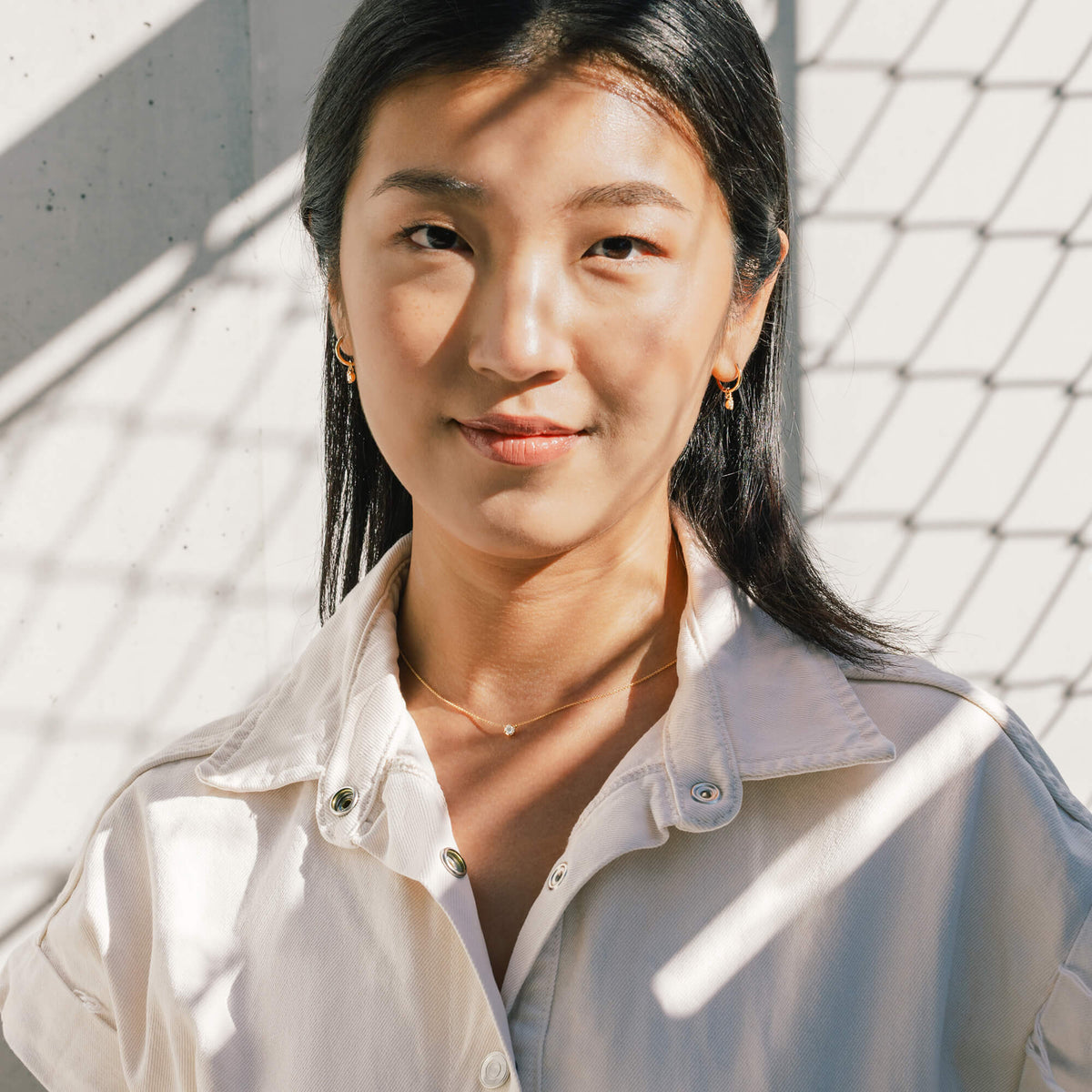 Outdoor studio portrait of model Hye Won Jang styling the BY TONIN Essential Diamond Necklace in 9K gold with a relaxed white denim shirt. An elegant reference for modern, intentional lifestyle wear and premium jewellery gifting in New Zealand.