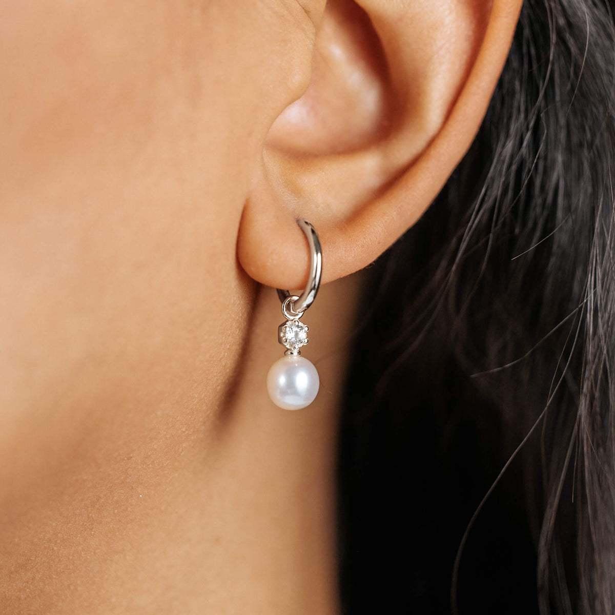 Silver hoop earring with a pearl drop on ear