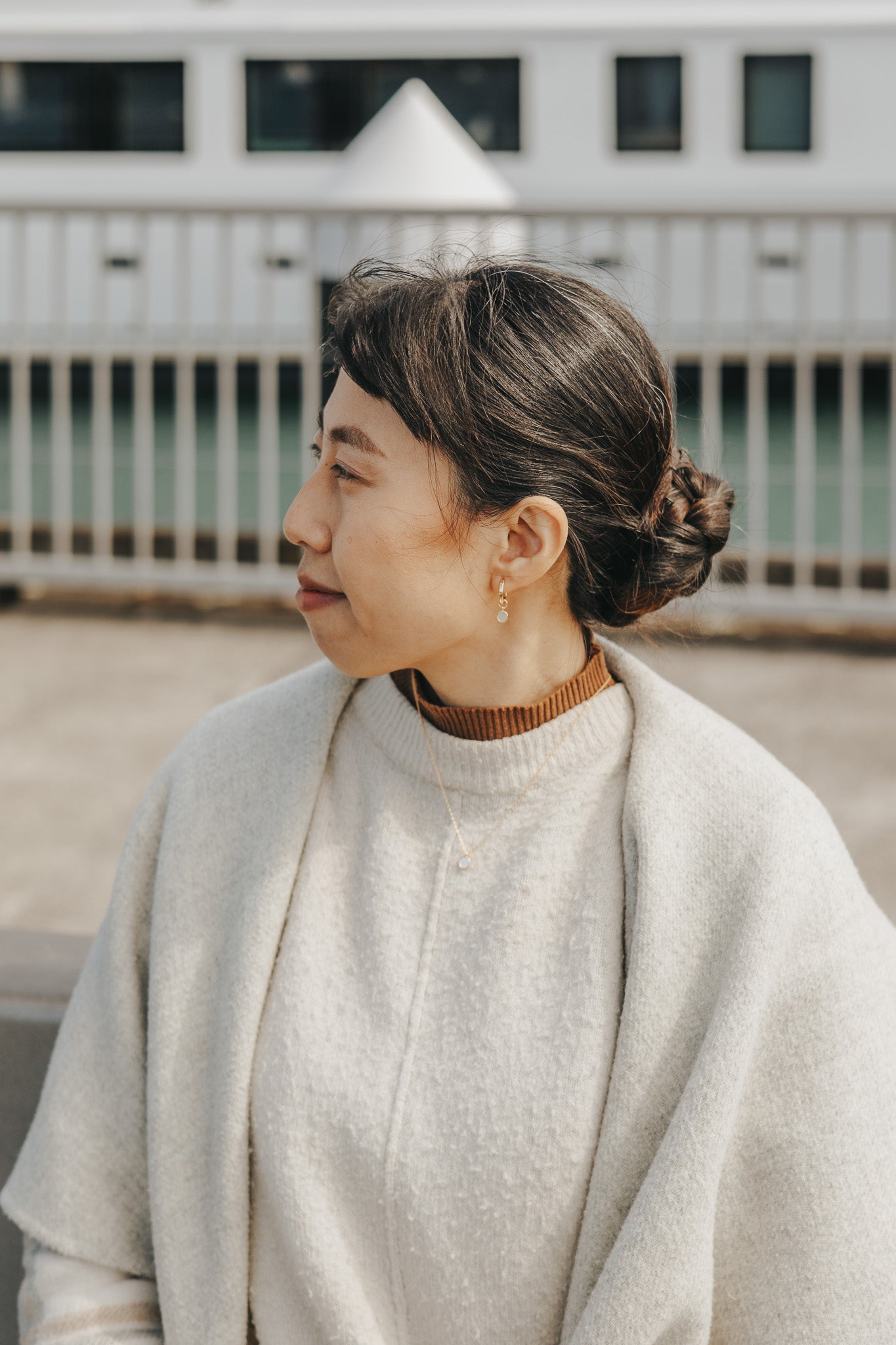 Sierra Truong wearing a light-colored coat and brown sweater outdoors with a blurred background
