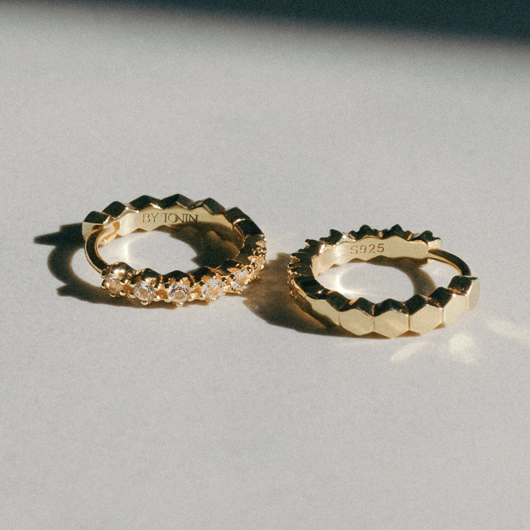 Two gold hoop earrings on a light gray background