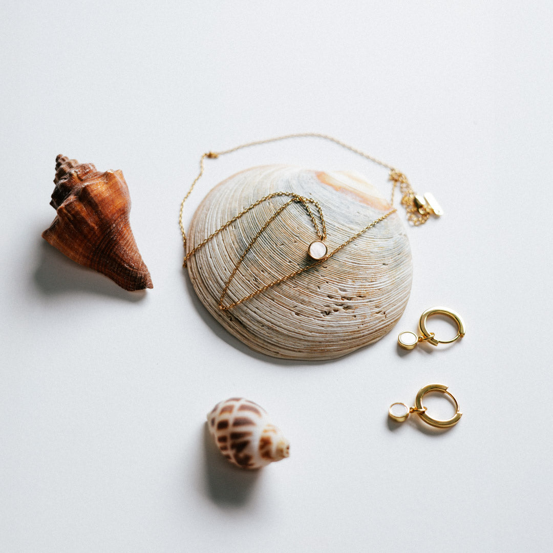 Gold mother of pearl jewellery set with shells on a light background