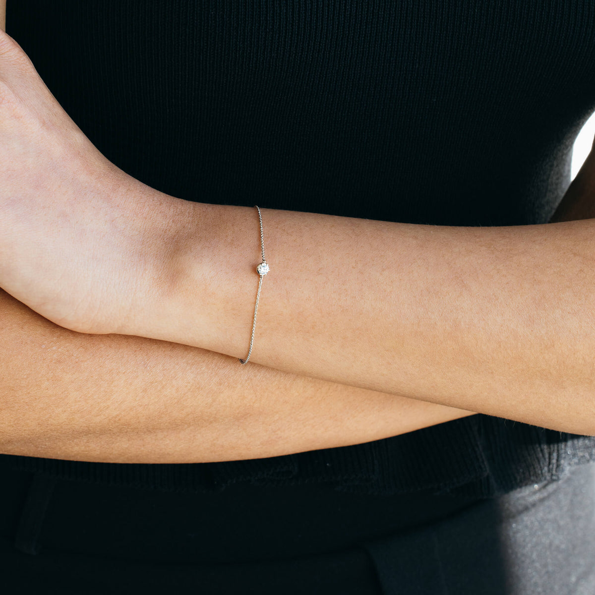 A model wearing the minimalist 925 sterling silver diamond bracelet with arms folded. The image demonstrates how the fine silver chain bracelet sits subtly against the skin, ideal for stacking.