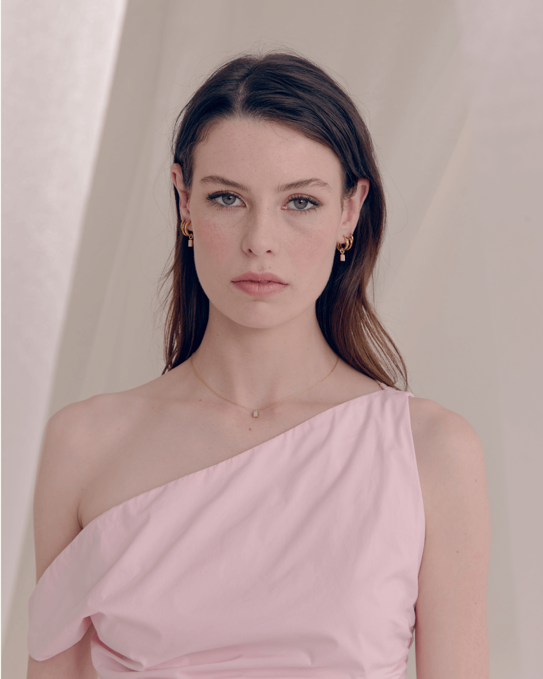 Studio Portrait - Model wearing Mother of Pearl pendant necklace and hoop earrings in a pink top.