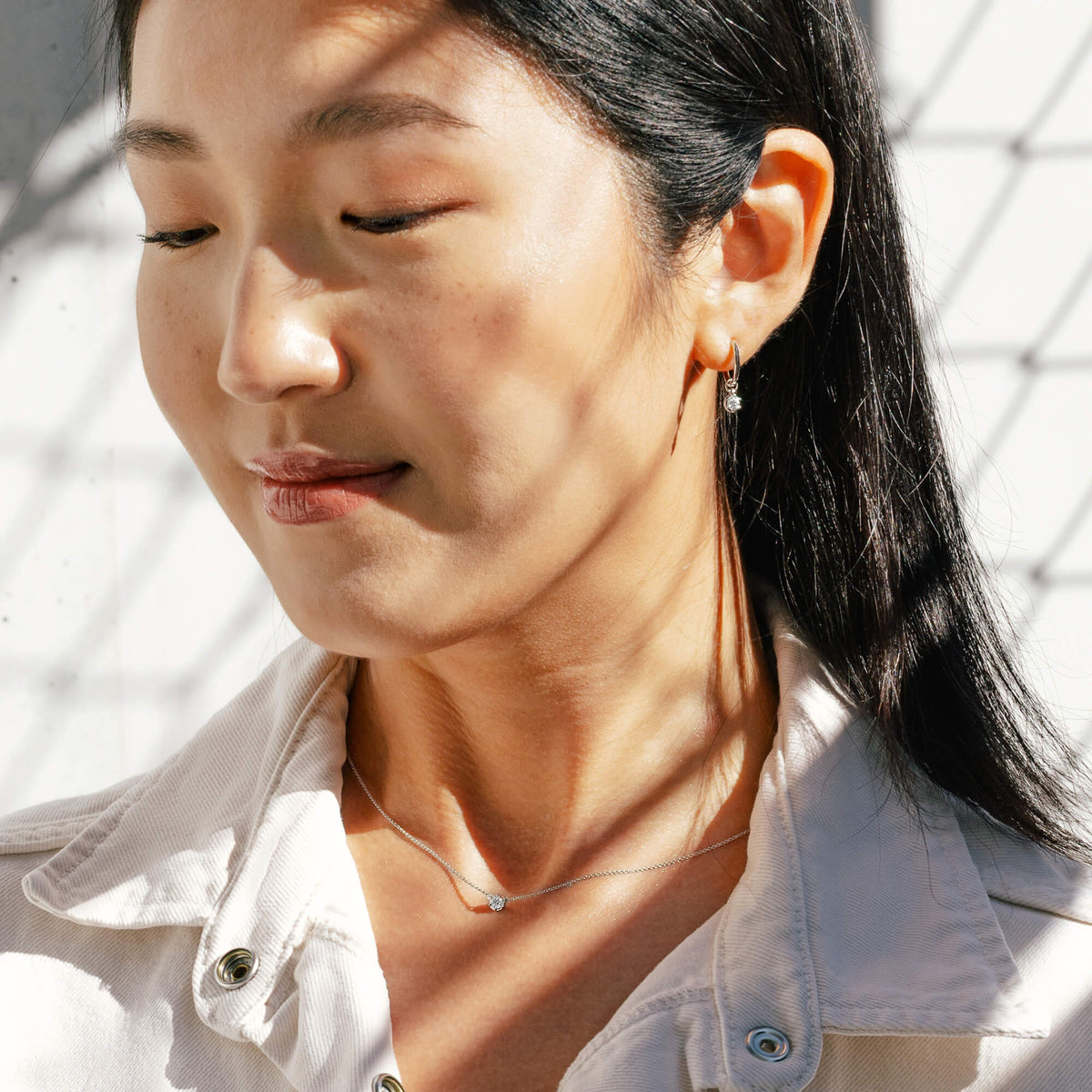 Lifestyle portrait of model Hye Won Jang wearing the 925 sterling silver diamond drop hoop earrings paired with the matching delicate chain necklace from the Essential Diamond Collection by BY TONIN, demonstrating clean everyday jewellery styling.