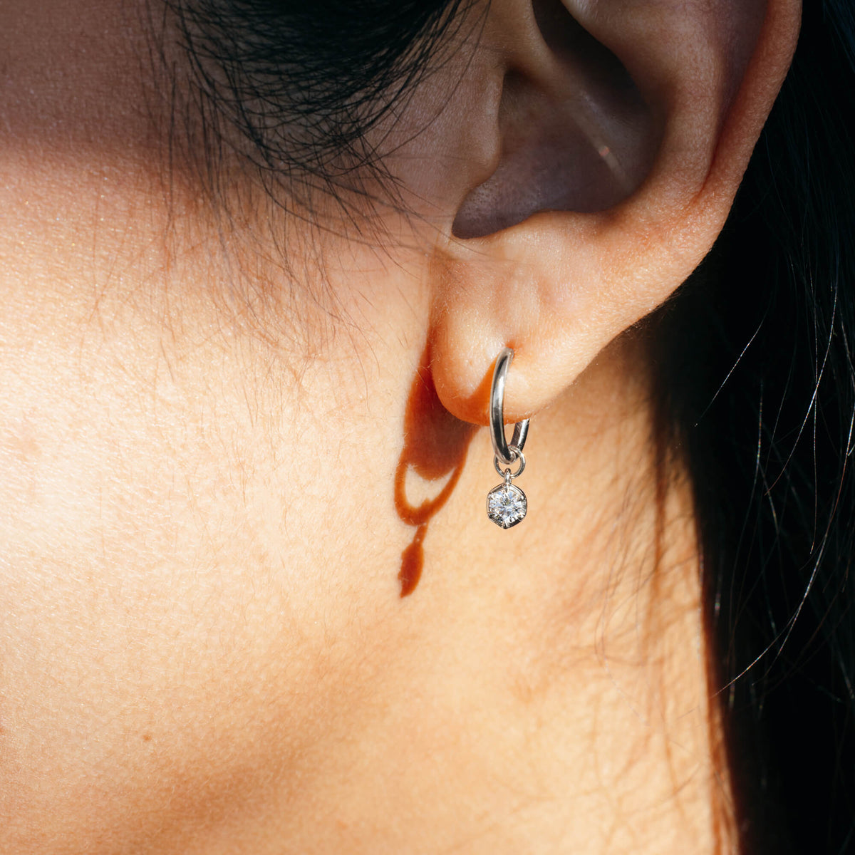 Macro profile view of the BY TONIN Essential Diamonds Drop Hoop Earrings in 925 sterling silver, showing a single 0.2 carat brilliant-cut lab diamond charm hanging from a fine silver hoop. Designed in NZ for intentional daily wear