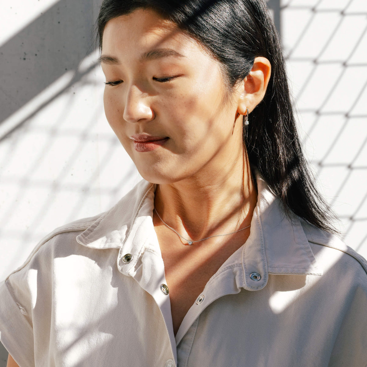 Lifestyle portrait of Hye Won Jang featuring the 0.2 carat lab diamond pendant necklace styled alongside coordinating sterling silver drop hoop earrings from the BY TONIN Essential Diamond Collection, offering a considered look for modern bridal or everyday gifting.