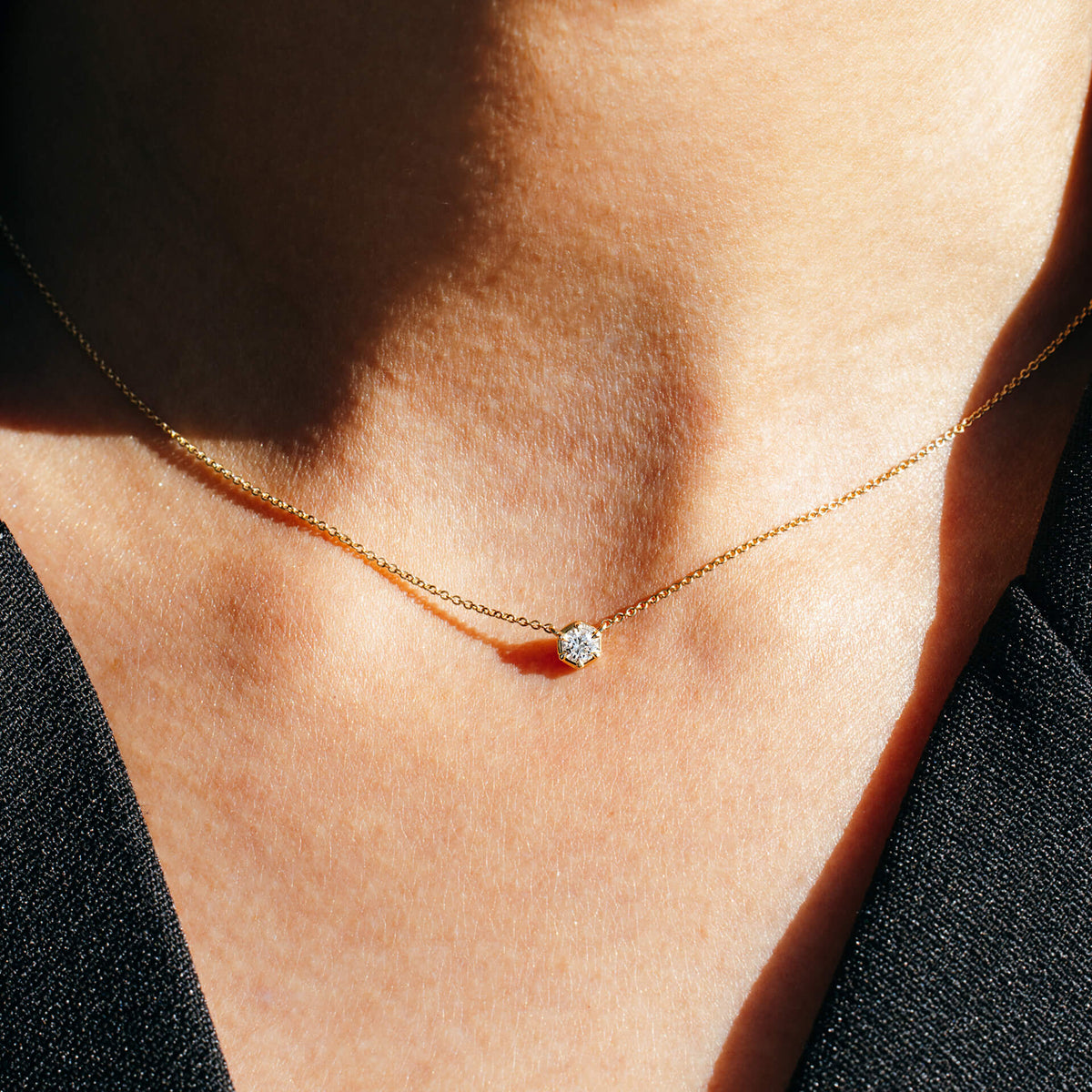 Close-up of the BY TONIN Essential Diamonds Pendant Necklace in 9K gold, highlighting how the 0.2 ct lab-grown diamond sits elegantly in a V-neckline against a black blazer. Designed in NZ for contemporary everyday wear.
