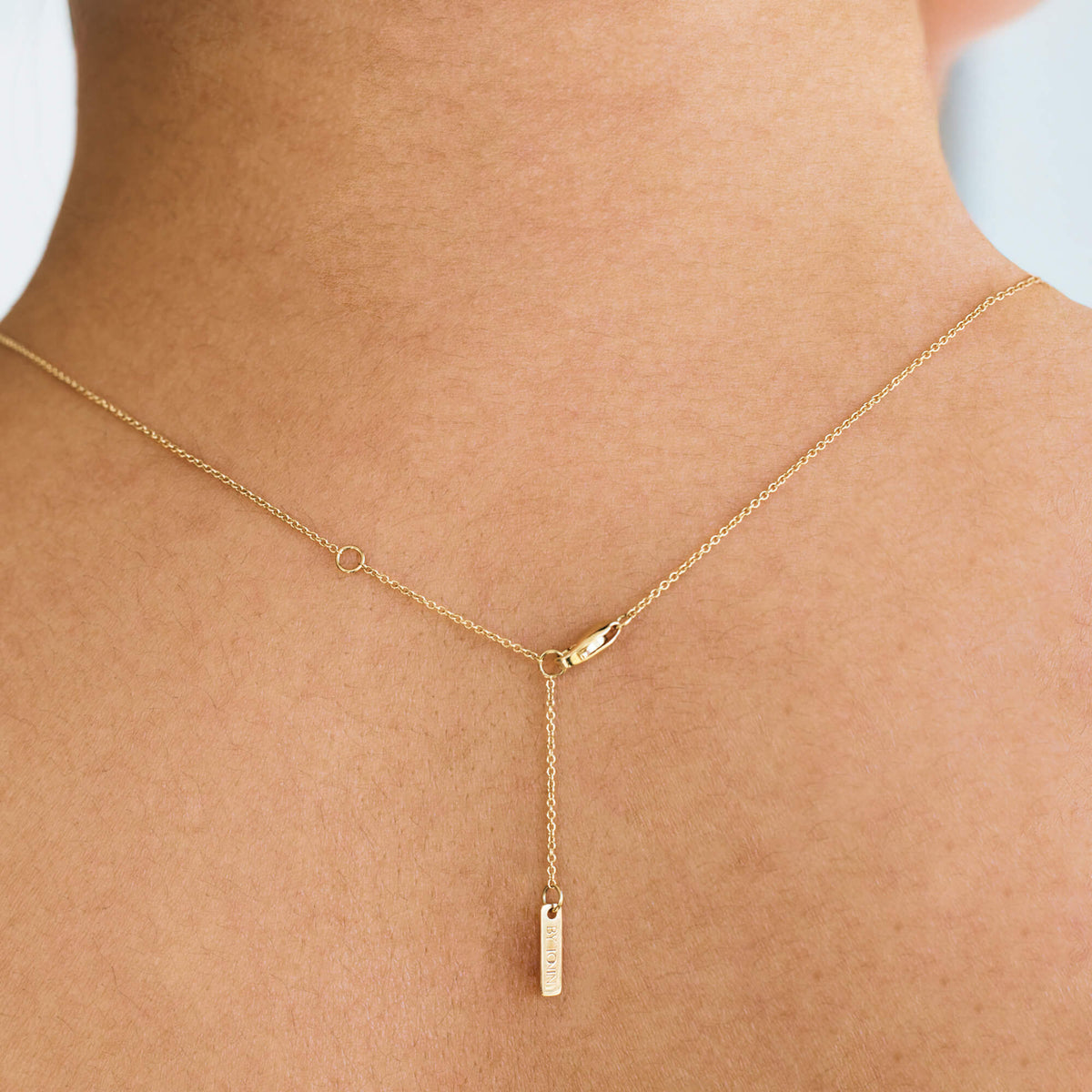Detailed view of the back of the neck showing the adjustable extension chain, secure lobster clasp, and engraved signature brand tag of the BY TONIN 9K gold diamond necklace, highlighting premium craftsmanship and quality hardware.