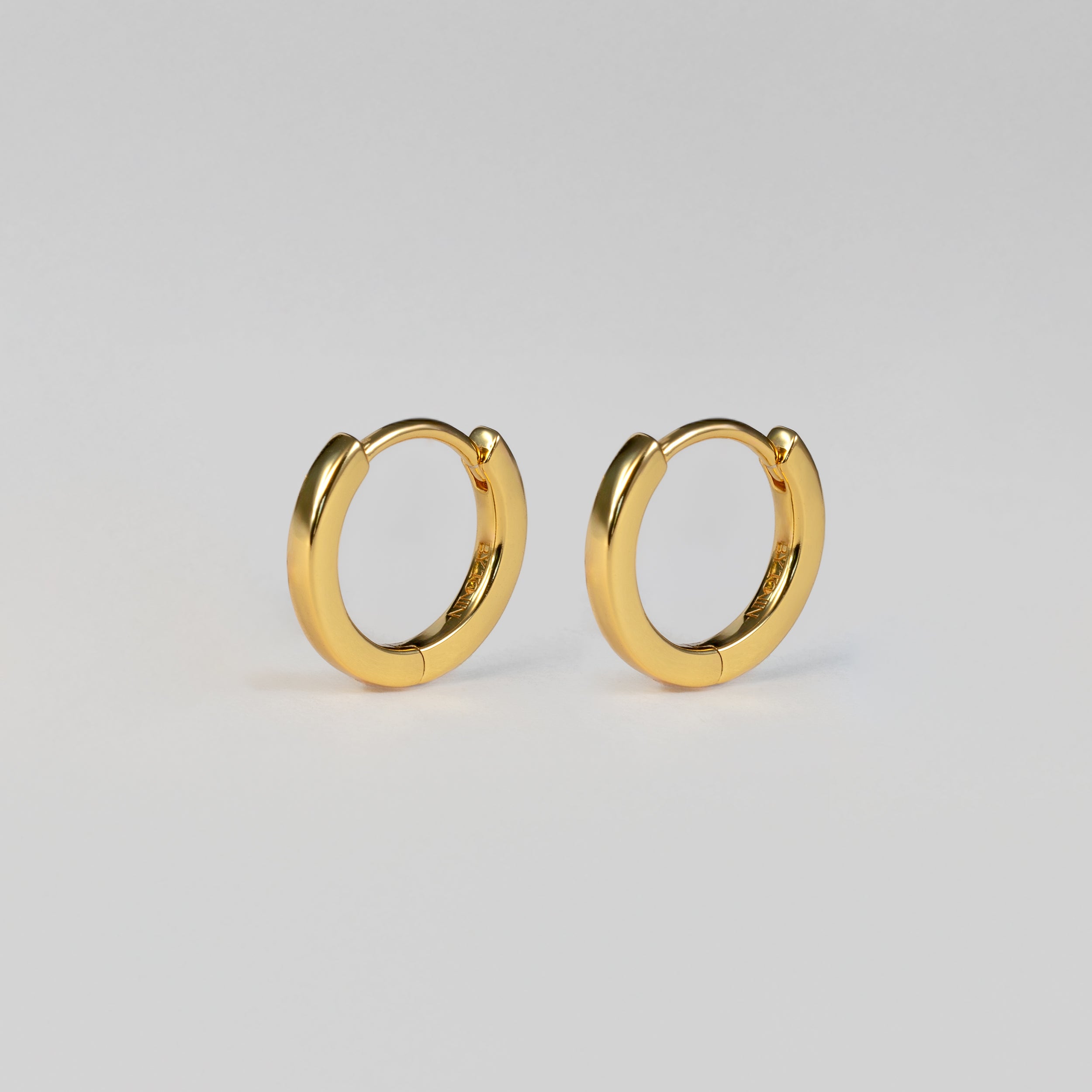 Elevate your everyday style with BY TONIN Heritage gold mini hoop earrings, featuring a flawless, polished finish for timeless elegance.