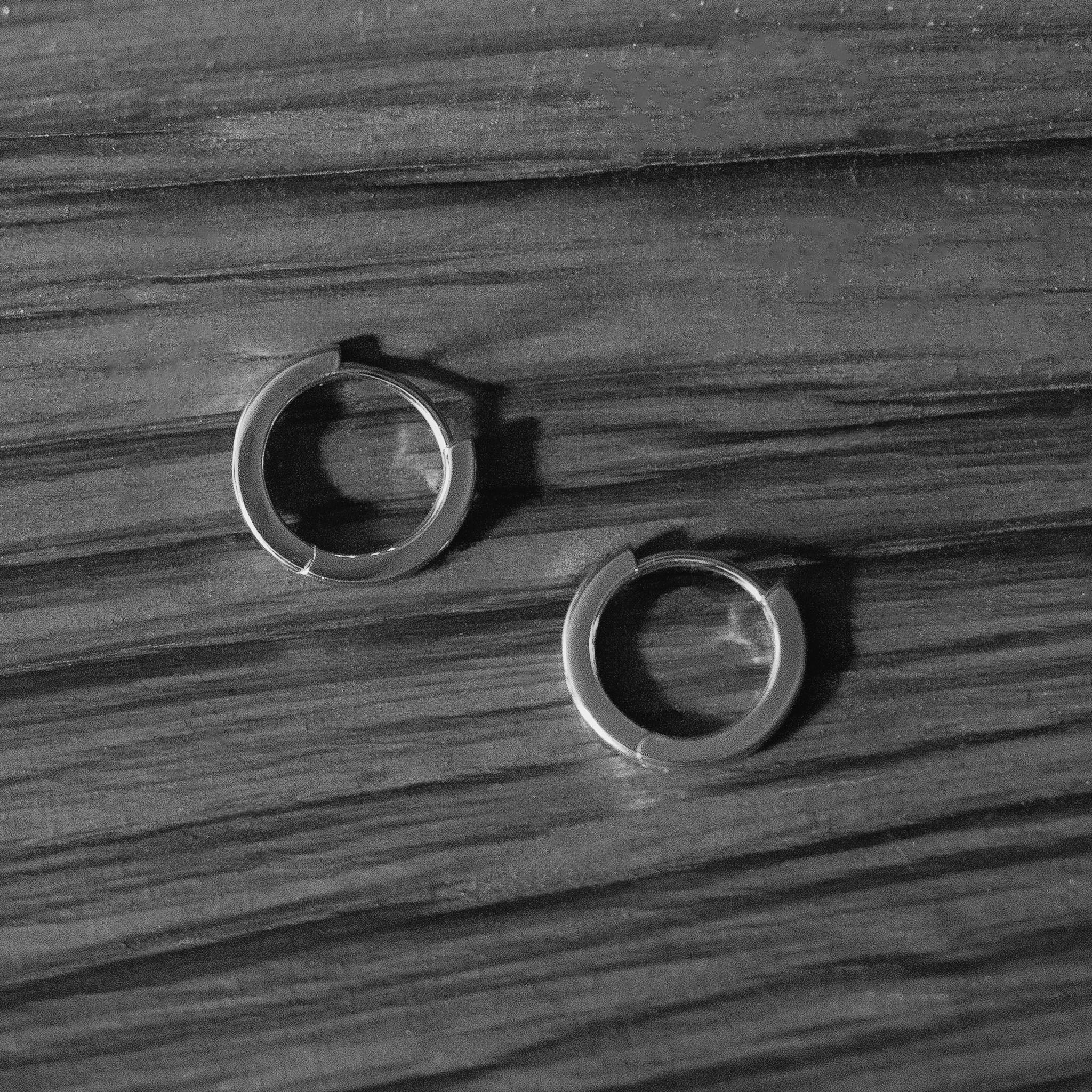 Embrace timeless versatility with BY TONIN's Heritage gold plated mini hoop earrings, elegantly displayed on a wooden surface in a classic black and white composition.