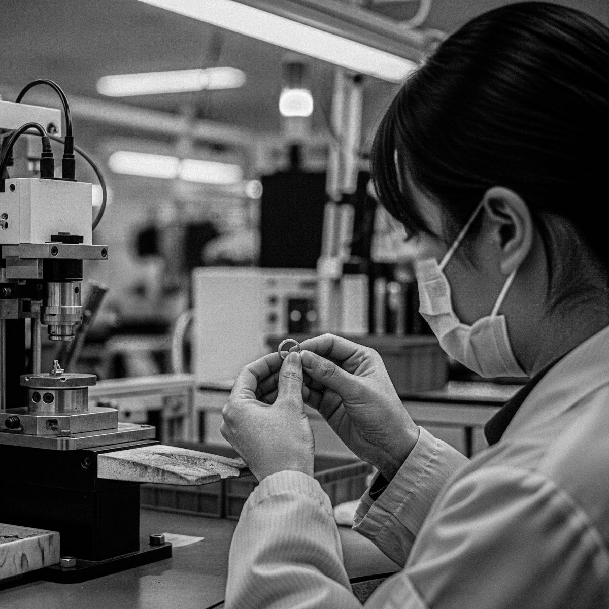 Witness BY TONIN's commitment to flawless quality: a masked artisan meticulously inspects a piece of jewellery with precision equipment in our dedicated workshop, ensuring every detail meets perfection.