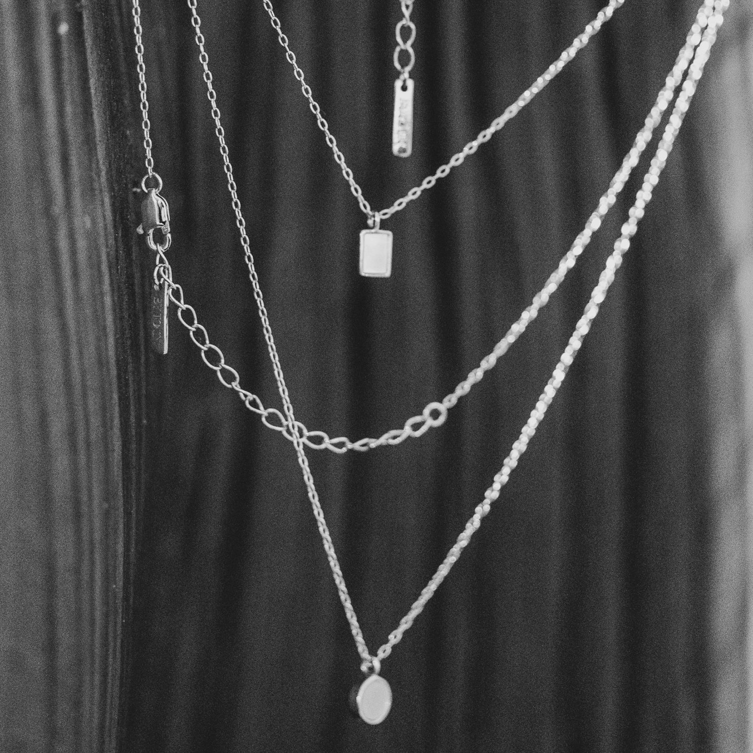 Master the art of layering with BY TONIN's exquisite collection of 10k Gold Plated necklaces, featuring a harmonious blend of rectangular, disc, and varied chain designs in a chic black and white composition.